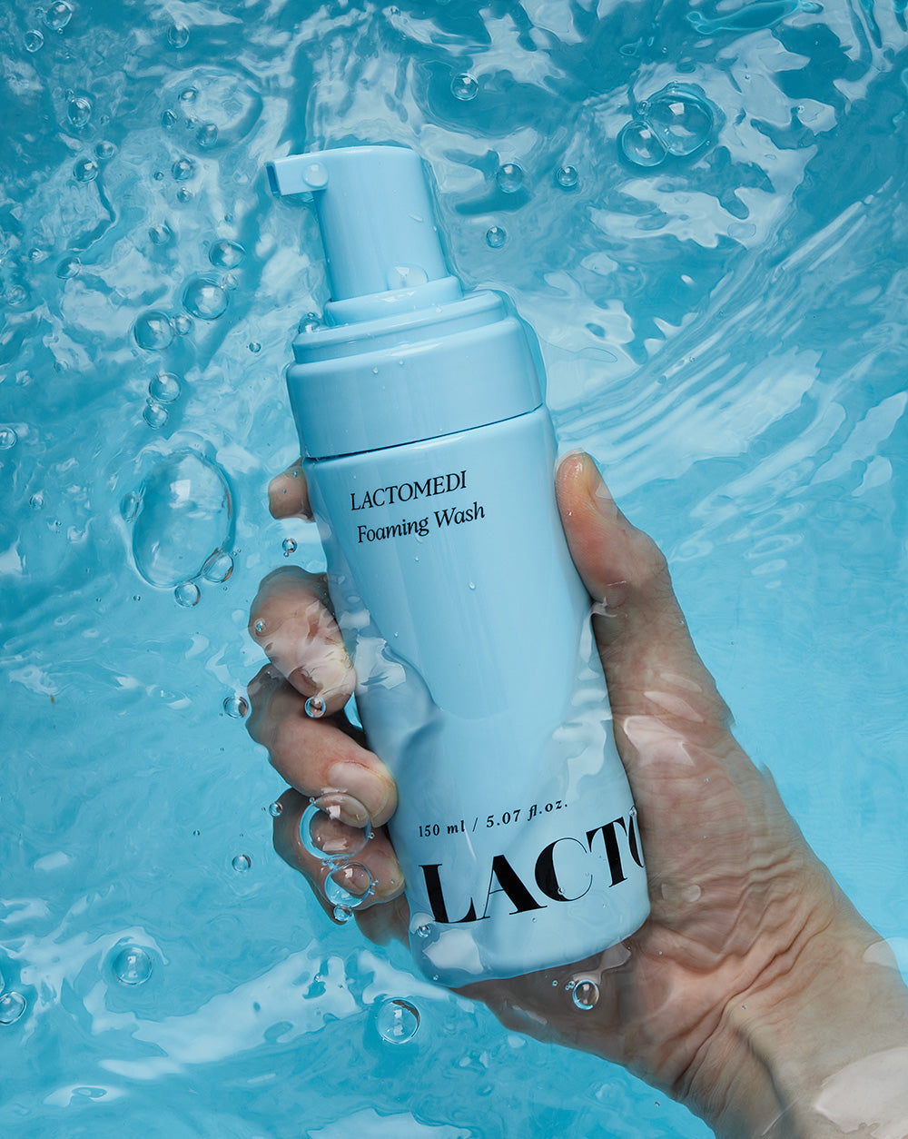 A hand holding Foaming Wash under water