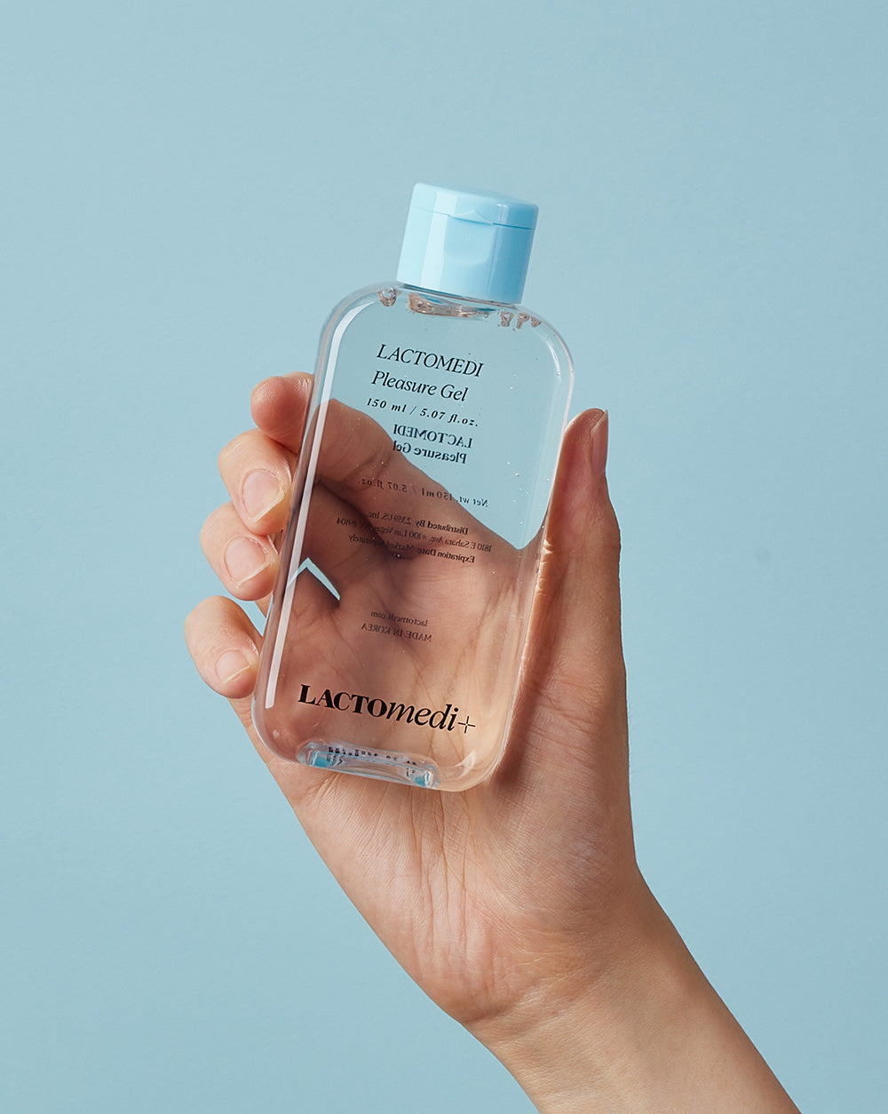 A hand holding a bottle of pleasure gel